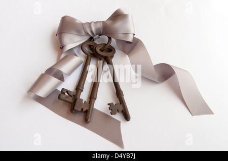 Drei rostige Antik Vintage Keys mit Schlüsselring auf Seide Silber Schleife gebunden Stockfoto