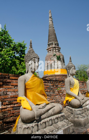 Thailand, Ayutthaya. Wat Phra Chao Phaya Thai. Sitzende Buddha-Statuen in gelben Gewänder gekleidet, glockenförmigen Chedi Tempel. UNESCO Stockfoto