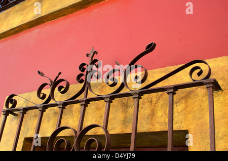 Sicherheit ein Schmiedeeisen Gitter in Oaxaca, Mexiko, auf einer gelben und orangefarbenen verputzten Wand. Stockfoto