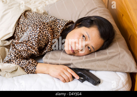 Horizontale Foto Reife Frau mit Waffe, Pistole, während im Bett Stockfoto