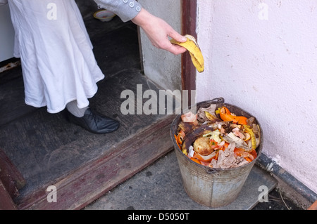 Eine Frau fällt Abfall in in einen Kompost-Eimer vor der Inbetriebnahme auf den Kompost. Stockfoto