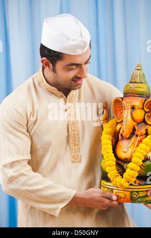 Maharashtrian Mann hält eine Statue von Lord Ganesha auf Ganesh Chaturthi Stockfoto