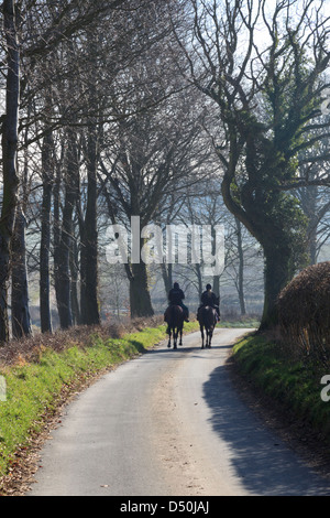 Zwei Reiter Reiten entlang einer Landstraße in Hampshire Stockfoto