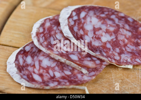 Salami-Stücke auf Holztisch Stockfoto