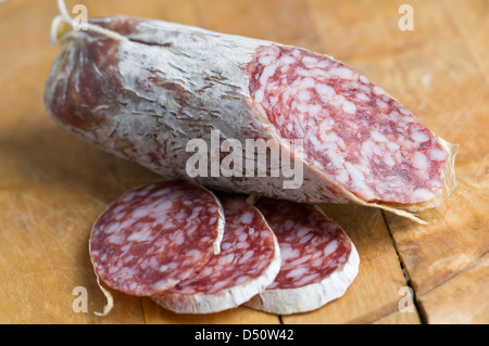 Salami-Stücke auf Holztisch Stockfoto