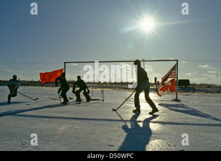 Kanada; USA; Russland-Fahnen auf kanadischen Jungs spielen Pond Hockey im Winter auf einem Bauernhof im Freien in Ontario; Kanada Stockfoto