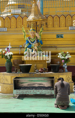 Eine junge Frau betet vor einem planetarischen Post in der Shwemawdaw Pagode in Bago, Myanmar. Stockfoto