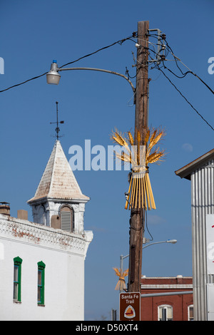 Eine Metall Weizen Skulpturen auf Lichtmasten im Vordergrund und eine Kirche im Hintergrund, Ellinwood, Kansas, USA Stockfoto