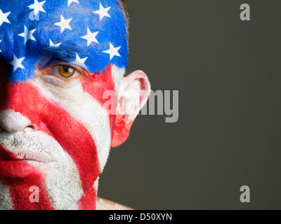 Mann mit seinem Gesicht gemalt mit der Flagge der USA. Der Mann ist traurig und fotografischen Komposition lässt nur die Hälfte des Gesichts. Stockfoto