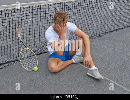 Enttäuscht Tennisspieler, sitzen auf dem Boden hielt seinen Kopf. Stockfoto