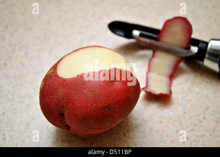 Eine rote Kartoffel schälen Stockfoto