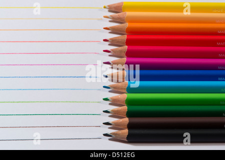 Close-up Detail von scharfen bunte Bleistiftzeichenstifte gelegt Seite an Seite auf weißem Papier Hintergrund von Zeilen in jeder Farbe - Yorkshire, England, UK. Stockfoto