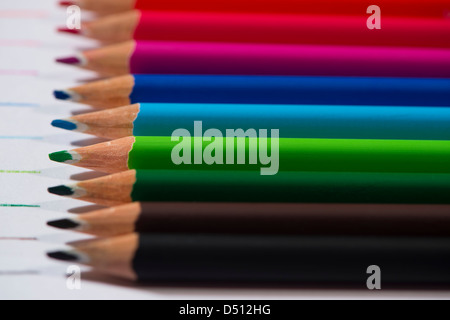 Close-up Detail von scharfen bunte Bleistiftzeichenstifte gelegt Seite an Seite auf weißem Papier Hintergrund von Zeilen in jeder Farbe - Yorkshire, England, UK. Stockfoto