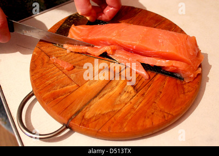 Bild von Hand schneidet Scheiben von roter Fisch Stockfoto