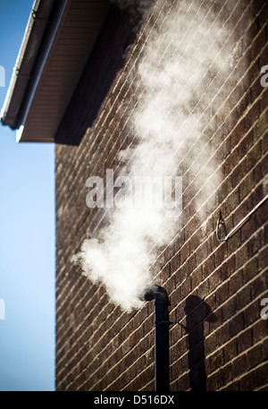 Dampf steigt von einer Zentralheizung Kessel Outlet Rauchrohr an einem Wintermorgen. Stockfoto