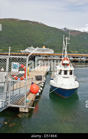 Kleine Patrouillenboot vertäut im Hafen von Andalsnes, mit dem Kreuzfahrtschiff Aurora verankert im Romsdalfjord jenseits. Stockfoto