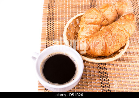 Frische und leckere französische Croissants in ein Korb und eine Tasse Kaffee serviert isolierten auf weißen Hintergrund Stockfoto