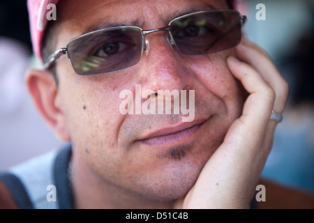 Mann mit Hand unter Kinn, Schattierungen und Cap Stockfoto