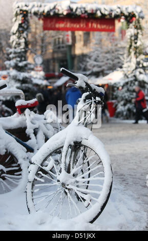 Verschneite Fahrräder stehen vor einem Weihnachtsmarkt in Hamburg, Deutschland, 18. Dezember 2010. Schneefall und eisiger Kälte bestimmen das Wetter in Hamburg. Foto: Malte Christen Stockfoto