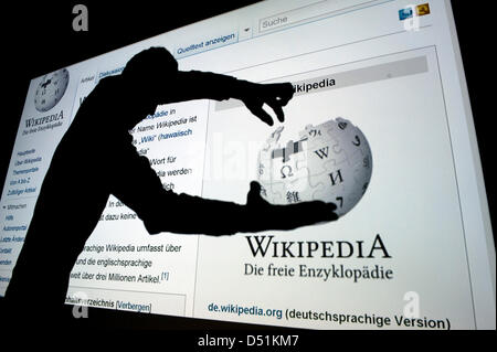 Die Abbildung zeigt die Silhouette eines Mannes hält das Logo einer abgeschirmten Projektion von der Website der Online-Enzyklopädie Wikipedia in Berlin, Deutschland, 22. Dezember 2010. Wikipedia feiert seinen 10. Geburtstag am 15. Januar 2011. Foto: Robert Schlesinger Stockfoto