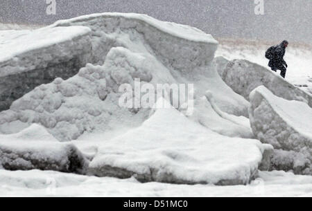 Kinderwagen zu Fuß passieren m hohe Barrieren aus Eis und Schnee im baltischen Seasside Resort in Zingst, Deutschland, 27. Dezember 2010. Eine Mischung aus starken Frost, Wind, Schnee und Eis haben eine bizarre Winterlandschaft geschaffen. Foto: Bernd Wuestneck Stockfoto