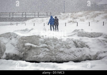 Kinderwagen zu Fuß passieren m hohe Barrieren aus Eis und Schnee im baltischen Seasside Resort in Zingst, Deutschland, 27. Dezember 2010. Eine Mischung aus starken Frost, Wind, Schnee und Eis haben eine bizarre Winterlandschaft geschaffen. Foto: Bernd Wuestneck Stockfoto