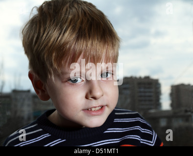 Junge sitzt auf einem Fensterbrett gegen Straße Stockfoto