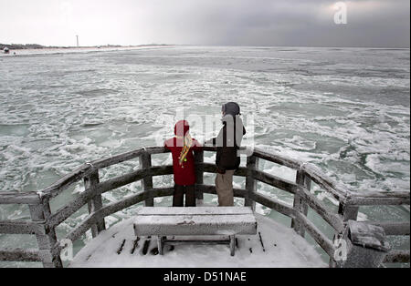 Leute betrachten die eisige Ostsee auf einer Brücke in Wustrow auf der Halbinsel Fischland, Deutschland, 30. Dezember 2010. Anhaltende Kälte frieren langsam Küstengewässer. Foto: Bernd Wuestneck Stockfoto