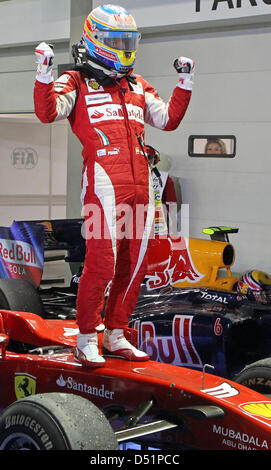 Spanischen Formel-1-Fahrer Fernando Alonso Ferrari-Team steht gekleidet in voller Montur auf der Motorhaube seines Rennwagens und Jubel nach dem Sieg der Grand Prix von Singapur auf dem Marina Bay Street Circuit in Singapur, 26. September 2010. Foto: Jan Woitas Stockfoto