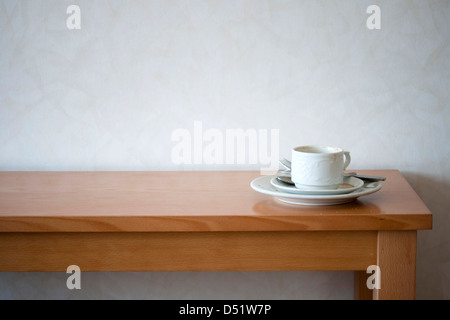 Eine gebrauchte Tasse Kaffee an einem langen Holztisch. Stockfoto