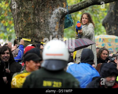 Ein Mädchen Feuer eine Wasserkanone wieder bei Polizei in Kampfmontur während der Proteste gegen die stark umstritten Railway Station Projekt Stuttgart 21 in Stuttgart, Deutschland, 30. September 2010. Der besetzte Baum ist Bestandteil einiger 300 Bäume, die im Rahmen der stark umstrittenen 4,1 Milliarden-Euro-Projekt gefällt werden ' Stuttgart 21', die eine Transformation der Stuttgarter Zentrale Stati sieht Stockfoto