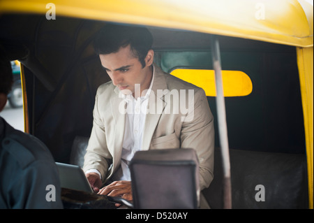 Geschäftsmann mit Laptop während der Fahrt in einem Auto-Rikscha Stockfoto