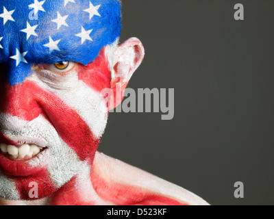 Mann mit seinem Gesicht gemalt mit der Flagge der USA. Der Mann ist aggressiv und fotografischen Komposition lässt nur die Hälfte des Gesichts. Stockfoto