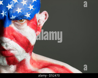 Mann mit seinem Gesicht gemalt mit der Flagge der USA. Der Mann ist ernst und fotografischen Komposition lässt nur die Hälfte des Gesichts. Stockfoto