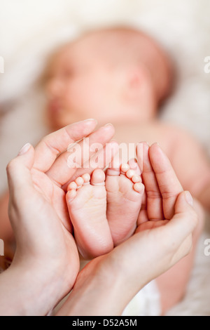 Mutters Hände halten kleine Babys Füße Stockfoto