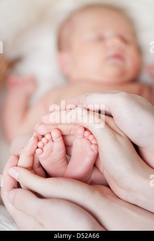 Mutters Hände halten kleine Babys Füße Stockfoto