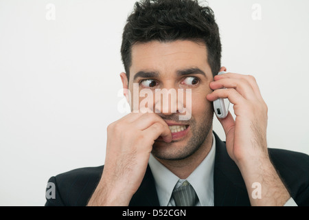 Mittleren Erwachsenenalter Geschäftsmann reden über Handy mit ängstlichen Ausdruck Stockfoto