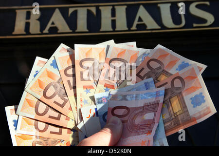 Eine Hand hält Banknoten vor dem Rathaus von Parchim, Deutschland, 4. März 2010. Finanzlage des Landes Meckelnburg-Vorpommern Commuities verbessert im Jahr 2008. Insgesamt 642 801 Gemeinden - oder 80-Prozent - hatte ihre finanzielle Leistungsfähigkeit garantiert, die Ministry of Interiors-Berichte. Foto: Jens Büttner Stockfoto