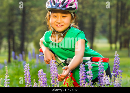Asiatische Mädchen sitzen auf Fahrrad in Wiese Stockfoto
