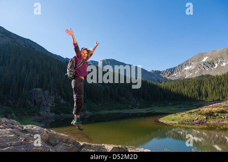 Kaukasische Wanderer springen vor Freude auf Findling Stockfoto