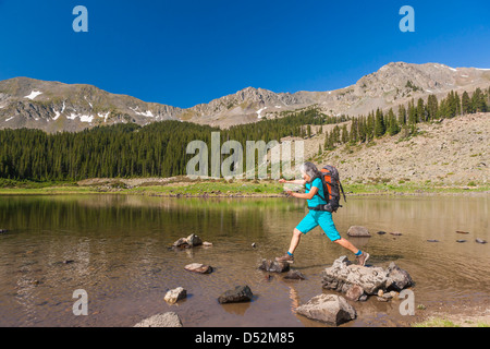 Hispanische Wanderer Klettern auf Felsen im See Stockfoto