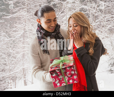 Mann die Freundin Geschenk im Schnee Stockfoto