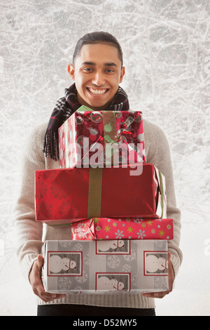 Hispanic Mann hält Stapel Geschenke im Schnee Stockfoto