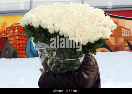 Ein Mann trägt einen großen Strauß weiße Rosen Kiew Bahnhof in Moskau, 7. März 2010 übergeben. In den Tagen vor dem internationalen Frauentag am 08 März, hoffe die Floristen für das Geschäft des Jahres: die Preise reichen von rund 1000 Rubel (25 Euro) für eine Flowergreeting bis 200000 Rubel (5000 Euro) für ein 60 Kilogramm Rosenstrauß 1001. Foto: Ulf Mau Stockfoto