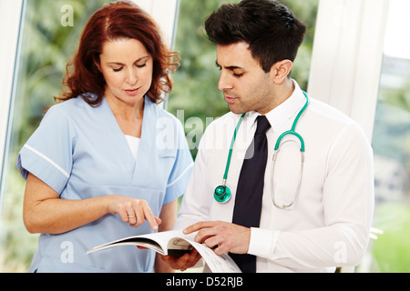 Arzt und Krankenschwester diskutieren Notizen Stockfoto