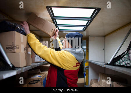 Ein Mitarbeiter von Deutsche Post DHL legt eine Paket in seinem Post-Bus an der ersten mechanischen Abgabestelle in Bochum, Deutschland, 20. März 2013. Es ist das zweite bundesweite System, das die Pakete automatisch liest und verteilt sie an den Transporter. Foto: Rolf Vennenbernd Stockfoto