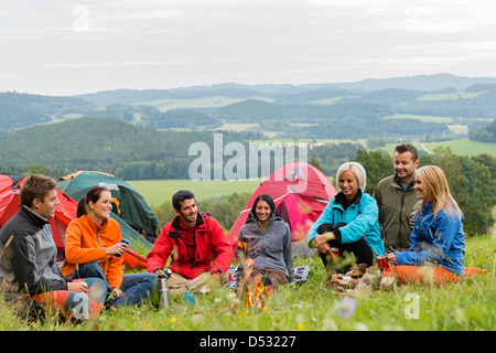 Lächelnde junge Menschen, die Natur neben Zelten und malerische Aussicht genießen Stockfoto