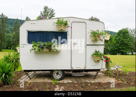 Alten Wohnwagen mit vielen hängenden Blumen in Töpfen Stockfoto