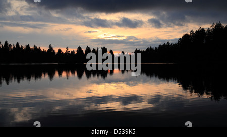 Fire In The Sky - Sonnenlicht von der untergehenden Sonne versucht, durch den bewölkten Abendhimmel zu brechen. Stockfoto