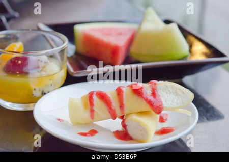 die Roll-Pfannkuchen mit Erdbeeren-Sirup und Sahne, Früchte auf Teller und Mix-Obst im Glas Stockfoto